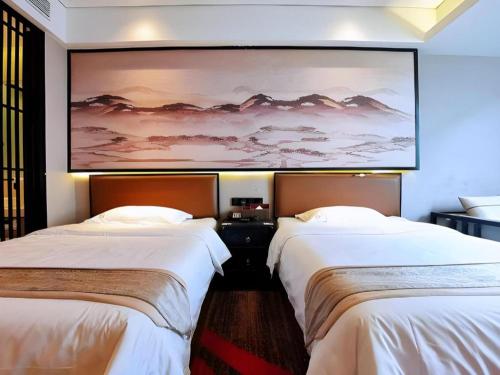 two beds in a hotel room with a large painting on the wall at Yuan Culture Hotel Shenzhen World Shajing in Shenzhen