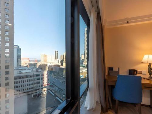 a room with a desk and a view of a city at Dalian Bohai Pearl Hotel in Dalian