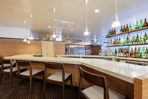 a restaurant with a bar with chairs and bottles at Art Hotel Niigata Station in Niigata