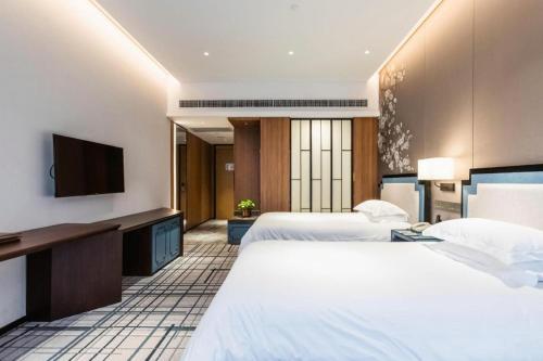 a hotel room with two beds and a flat screen tv at International Conference Hotel Nanjing in Nanjing