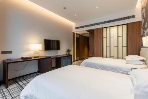 a hotel room with two beds and a television at International Conference Hotel Nanjing in Nanjing