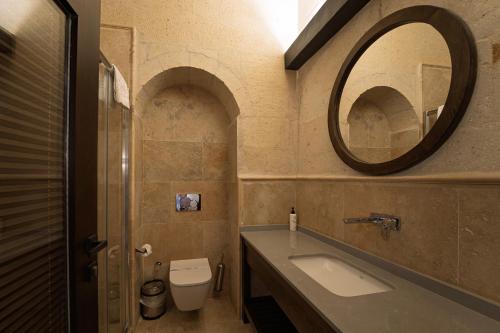a bathroom with a sink and a mirror and a toilet at Luvi Cave Hotel in Goreme