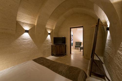 a bedroom with a bed and a tv in a room at Luvi Cave Hotel in Goreme