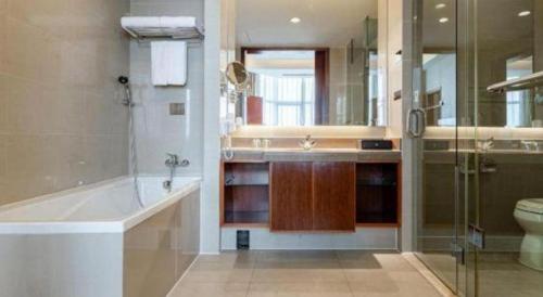 a bathroom with a tub and a toilet and a sink at Qingdao Blue Horizon Hotel Licang in Qingdao