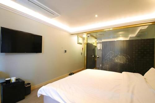 a bedroom with a bed and a flat screen tv at Jeju Sejong Hotel in Jeju
