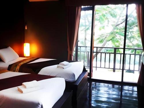 a hotel room with two beds and a balcony at Thaton Hill Resort in Mae Ai