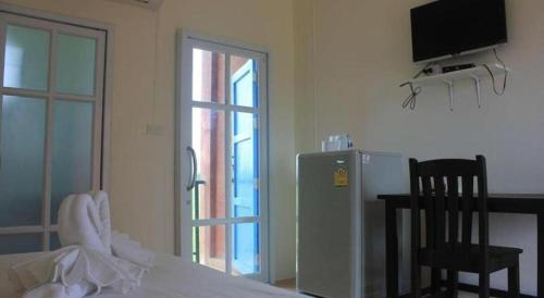 a bedroom with a refrigerator and a table with a chair at Le Bar Tarry Hotel in Loei