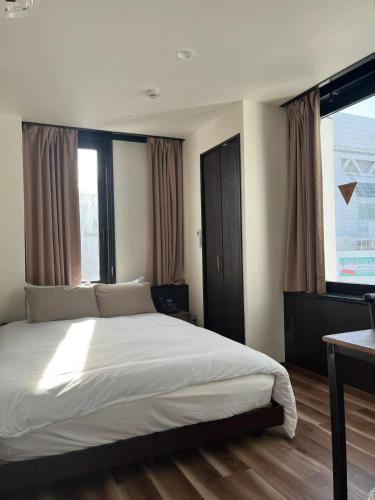 a bedroom with a large white bed with windows at daren stay in Tokyo