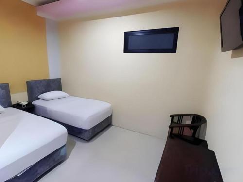 une chambre avec deux lits et une télévision à écran plat dans l'établissement Hotel Khalista, à Gurungsang