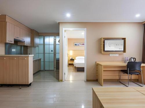 a kitchen with a desk and a room with a bed at City Comfort Inn Wuhan Hankou Railway Station West Square in Wuhan