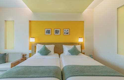 two beds in a hotel room with yellow walls at The Mirador in Mumbai