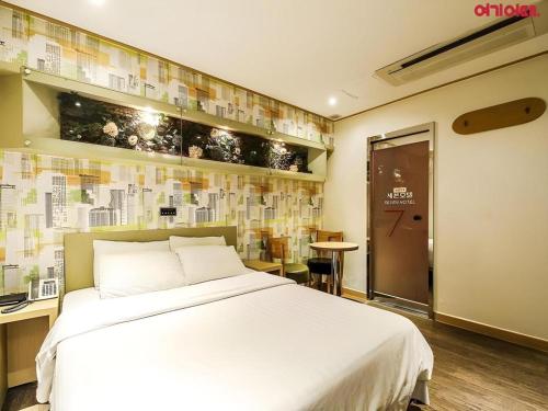 a bedroom with a large white bed and a desk at Seven Motel Ansan in Ansan