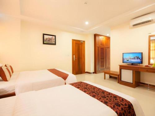 a hotel room with two beds and a television at Kirirom Crystal Hotel in Phnom Penh