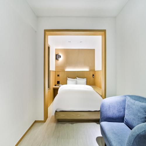 a bedroom with a bed and a blue couch at No 25 Hotel Gumi Wonpyeongdong in Gumi