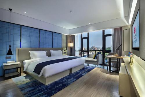 a bedroom with a large bed and a balcony at Echarm Hotel Guilin North High Speed Railway Station in Guilin
