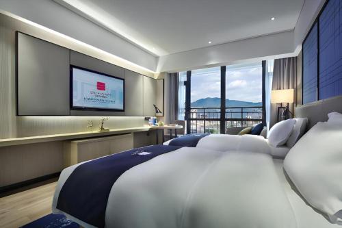 a bedroom with a large bed and a flat screen tv at Echarm Hotel Guilin North High Speed Railway Station in Guilin