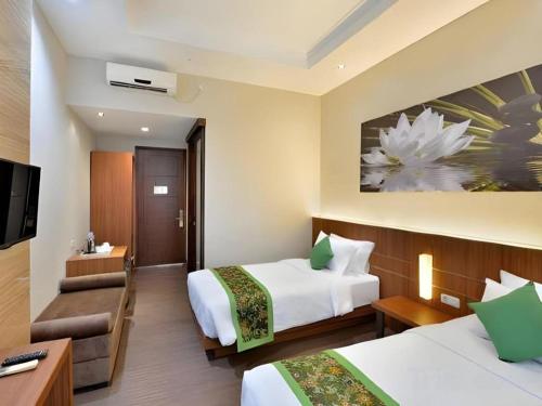 a hotel room with two beds and a television at Lotus Hotel Subang in Bandung