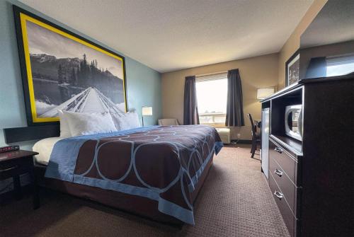 a hotel room with a bed and a television at Super 8 by Wyndham Edmonton South in Edmonton