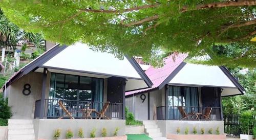 a house with chairs on the balcony of it at Rim Kaeng resort in Phetchaburi