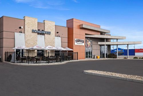 a restaurant with tables and umbrellas in front of a building at Days Inn & Suites by Wyndham Winkler in Winkler