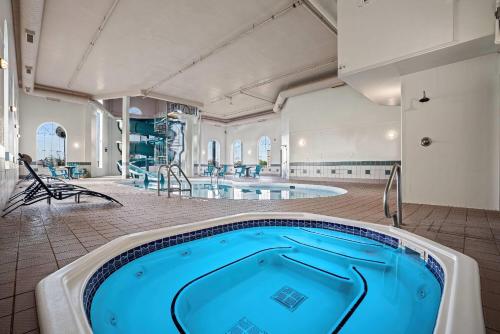 a large swimming pool in a room with a hot tub at Days Inn & Suites by Wyndham Winkler in Winkler