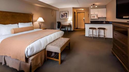 a hotel room with a large bed and a kitchen at Best Western Plus Orillia Hotel in Orillia