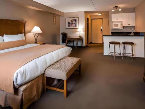 a hotel room with a large bed and a kitchen at Best Western Plus Orillia Hotel in Orillia