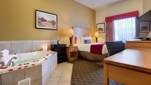 a hotel room with a bed and a bath tub at Best Western Plus Guymon Hotel and Suites in Guymon