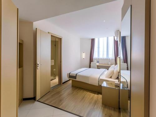 a hotel room with a bed and a mirror at City Comfort Inn Dangtu High Speed East Railway Station RT-Mart in Ma'anshan