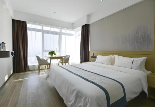 a hotel room with a large bed and a table at City Comfort Inn Dangtu High Speed East Railway Station RT-Mart in Ma'anshan