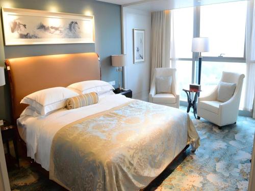 a bedroom with a large bed and two chairs at Xian Jue Vu Hotel in Xi'an