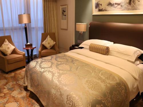 a bedroom with a large bed and two chairs at Xian Jue Vu Hotel in Xi'an