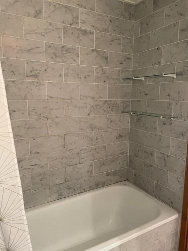 La salle de bains est pourvue d'une baignoire blanche et d'un mur en carrelage. dans l'établissement Résidence Bel Alp - BEL ALP 3 MAE-6771, à Saint-Gervais-les-Bains