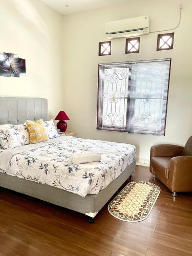 a bedroom with a bed and a chair and a window at Ndalem Suryo Guesthouse in Yogyakarta