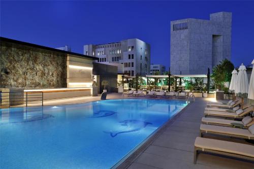a large swimming pool with chairs and a building at Signia by Hilton in Amman