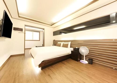 a bedroom with a large bed and a flat screen tv at H Hotel in Ulsan