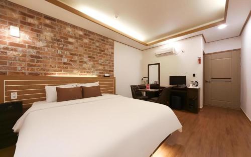 a bedroom with a white bed and a brick wall at H Hotel in Ulsan