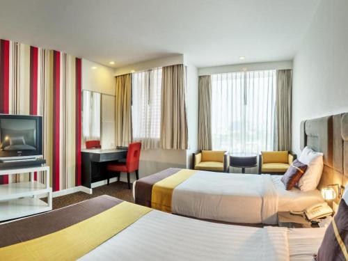 a hotel room with two beds and a television at Thamrongin Hotel in Bangkok