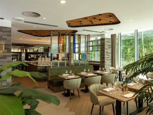 a restaurant with tables and chairs and windows at Hilton Garden Inn Brussels Airport in Diegem