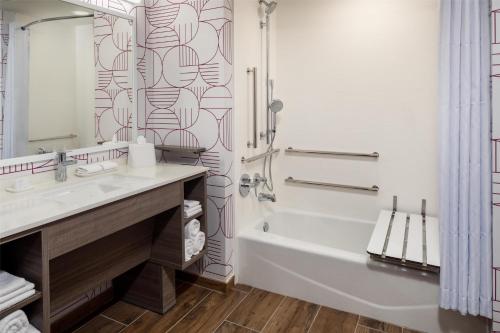 a bathroom with a tub and a sink and a shower at Home2 Suites By Hilton Clearwater St. Petersburg Ulmerton Rd in Clearwater
