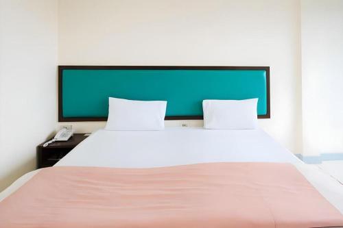 a large white bed with two pillows and a phone at Nice Beach Hotel in Rayong