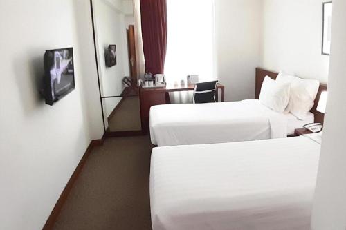 a hotel room with two beds and a tv at PARK HOTEL Cawang Jakarta in Jakarta
