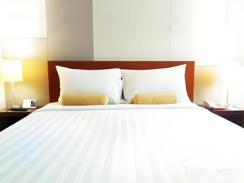 a large white bed with two pillows and two lamps at PARK HOTEL Cawang Jakarta in Jakarta