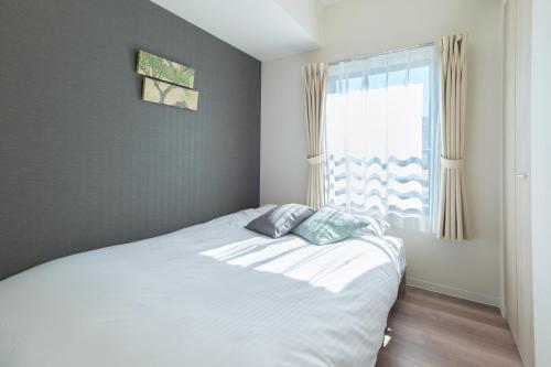a bedroom with a white bed and a window at AQUA RESIDENCE Sangenjaya by Tranova in Tokyo