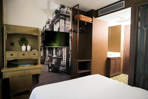 a bedroom with a bed and a desk and a tv at Largos Hotel in Hong Kong