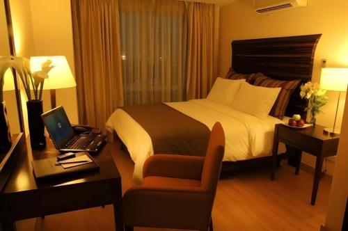 a hotel room with a bed and a desk with a laptop at Lancaster Hotel Manila in Manila