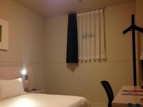 a bedroom with a bed and a desk and a window at Jinjiang Inn Pingyao Branch in Pingyao