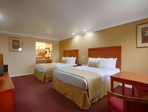 a hotel room with two beds and a table at Best Western Hanford Inn in Hanford