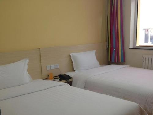 two beds sitting next to each other in a room at 7 Days Inn Hohhot Hailiang Xinhua Square Metro Station in Hohhot