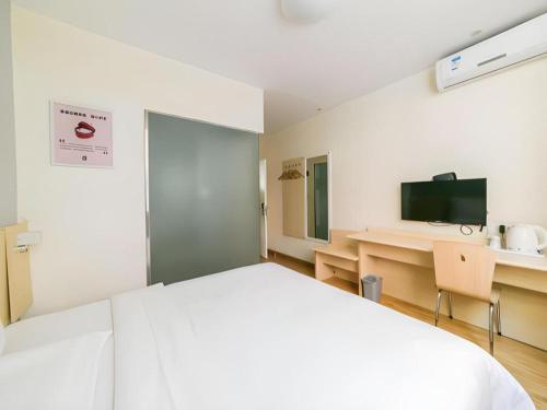 a room with a bed and a desk and a television at 7 Days Inn Hohhot Hailiang Xinhua Square Metro Station in Hohhot